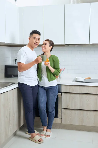 Lovely girl standing on the floor and talking with boyfriend. Young couple enjoying coffee in kitchen.