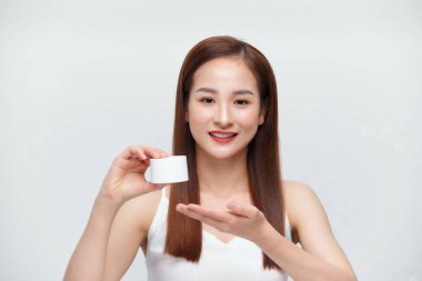 Gülümseyen genç bir kadın elinde krema şişesiyle