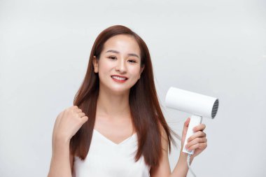 Saçlarını kurutan genç bir kadın.