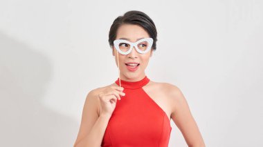 Elinde kağıt süslemeli fotoğraf kabini maskesi olan ciddi bir kadın. Düğün, doğum günü ve karnaval komik aksesuar konsepti.