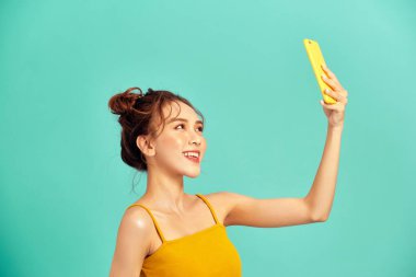 Güzel genç Asyalı kadın fotoğraf çekmek için telefon kullanıyor ya da video görüşmesi yapıyor..