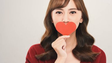 Çekici bir Asyalı kadının başı ve omuzları. Ağzı kalp şeklinde bir kağıt parçasıyla kaplıyken koyu gri gözleriyle kameraya bakıyor.