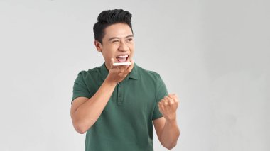 Beyaz arka planda izole bir şekilde telefonla konuşurken yüzüne ve hareketlerine şaşıran yakışıklı, heyecanlı bir adamın fotoğrafı.