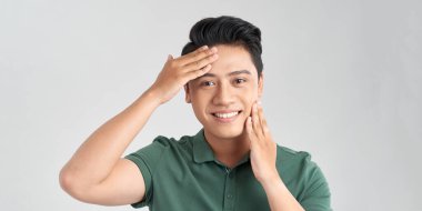 Beyaz arka planda yakışıklı Asyalı bir adamın portresi. Erkeklerin sağlığı ve güzelliği, kendine bakım, vücut ve cilt bakımı kavramı