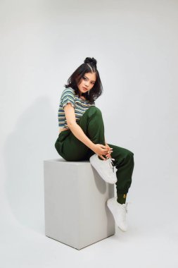 Güzel Asyalı bir kız. Ekinler içinde. Taburede oturup kameraya bakıyor.