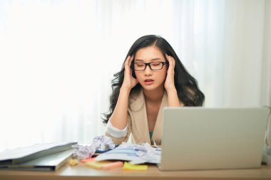 Uzak iş, teknoloji ve insan konsepti - ev ofisinde çalışan dizüstü bilgisayarı ve evrakları olan stresli genç kadın