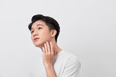 Genç adam yüzüne dokunuyor., 