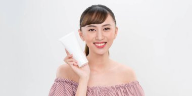 Güzellik Gençliği Cilt Bakımı Konsepti - Güzel Asyalı Kadın Yüz Portresi Tutma ve Krem Tüpü Ürünleri Sunumu.