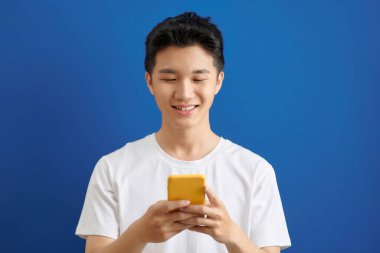 Yakışıklı genç adam cep telefonuyla mesaj yolluyor.,