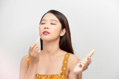 Kırmızı dudak parlatıcısı şişesi tutan seksi, gülümseyen genç bir kadının portresi.