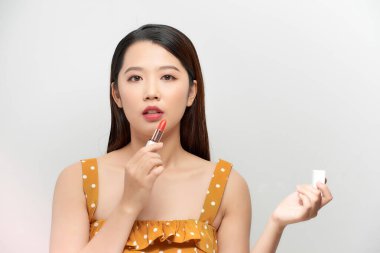 Kırmızı ruj tutan güzel genç bir kadın, beyaz arka planda izole edilmiş.