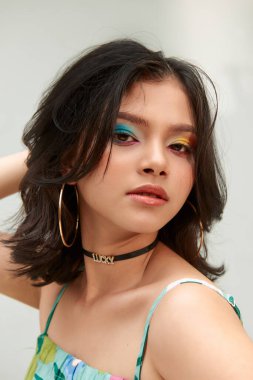 Gülümseyen, renkli, kalın gözlü, beyaz arka planda poz veren mutlu bir kadın.