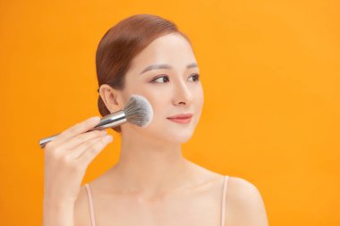 Güzellik. Makyaj. Güzel bir kadın makyaj fırçası kullanarak yüzüne kuru makyaj malzemesi sürüyor..