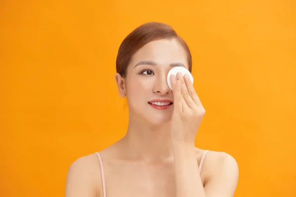 Happy smiling beautiful asian woman using cotton pad cleaning skin