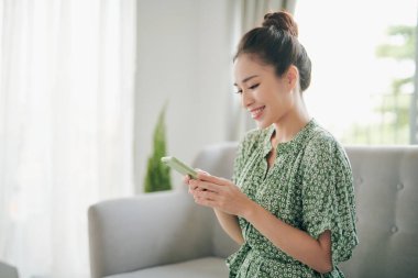 Genç ve çekici Asyalı bir kadın akıllı bir telefon görmek istiyor.