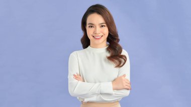 Mor bir arka planda kollarını kavuşturmuş mutlu bir kadının portresi.