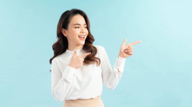 Güzel Asyalı kadın kopyalama alanını işaret ediyor. Mavi arkaplanda izole edilmiş.