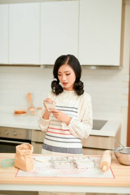 Evde kurabiye yaptığı için mutfakta genç bir kız var. 