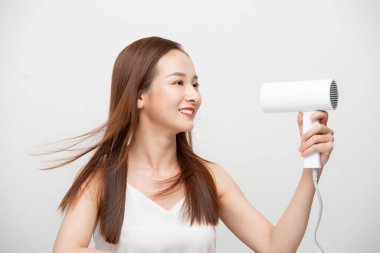 Çekici, güzel Asyalı kadın saç kurutma makinesiyle rüzgar üflüyor.