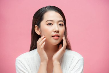 Güzellik ve Spa Konsepti. Temiz tenli, güzel genç bir kadın kendi yüzüne dokunuyor ve gülümsüyor.