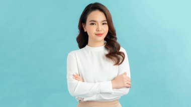 Kollarını katlayıp fotokopi çekilen gülümseyen genç bir kadının portresi mavi arka planda izole edilmiş.