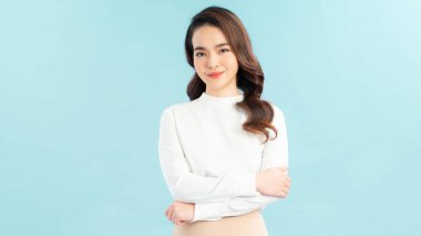 Kollarını katlayıp fotokopi çekilen gülümseyen genç bir kadının portresi mavi arka planda izole edilmiş.