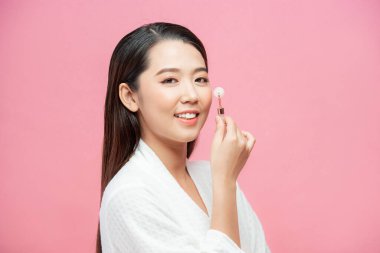 Mükemmel cilde sahip güzel bir genç kadın. Doğal kuvars taşlı bir gül kuvars yüz silindiri kullanıyor. 