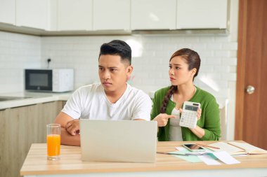 Finansal faturaları olan üzgün genç bir kadın evde bir erkekle kavga ediyor.