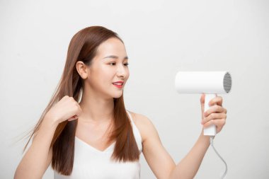 Çekici, güzel Asyalı kadın saç kurutma makinesiyle rüzgar üflüyor.