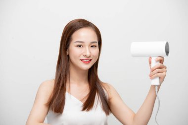 Saçını kurutan güzel bir kız beyaz arka planda saç kurutma makinesiyle..