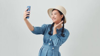 Çekici Asyalı kadın gün ışığında ayakta duruyor. Akıllı telefonuyla selfie çekiyor. 