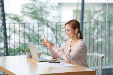 Genç Asyalı kadın oturma odasında dizüstü bilgisayar kullanıyor.