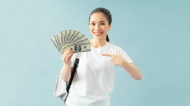 Sırt çantasında gülümseyen kız, işaret parmağı nakit para hayranı dolar banknotları