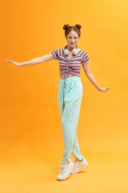 Sarı arka planda dans eden heyecanlı bayan.