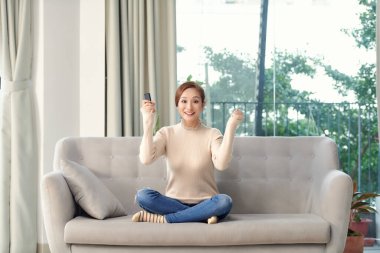 Evde kanepede oturan, evde televizyon izleyen genç bir kadının pozitiflik fotoğrafı güzel bir jest yaptı..