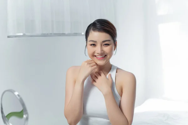 Portrait of beauty smiling asian woman applying lotion skin during her morning routine