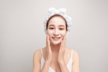 Yüzüne kilden maske takıp yaşlanmayı önleyici yöntemler kullanırken kendine güvenen bornozlu ve kafasında havluyla dolaşan kadının portresi.