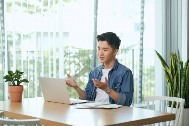 Yakışıklı bir adam. Sakallı yakışıklı adam sabahı oturma odasında geçiriyor ve görüntülü sohbet ediyor.