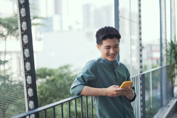 Happy man using mobile phone at balcony