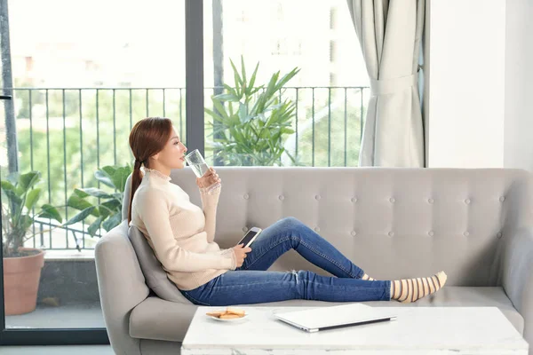 Evde su içen bir kadın ve seni evdeki oturma odasında bir kanepede otururken görmek.