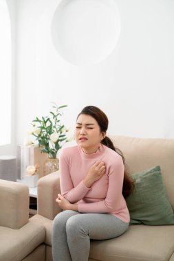 Asyalı güzel kadının derisi kurumuş ve oturma odasında dirseğini kaşıyor.