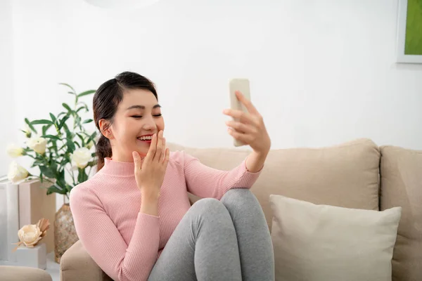 Glückliche Junge Frau Sitzt Auf Dem Sofa Und Hält Ihr — Stockfoto