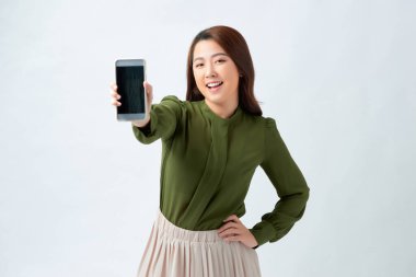 Parlak gülüşlü güzel bir bayan reklamınız için boş kopya ekranlı akıllı bir telefon gösteriyor.