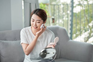 Yüzüne makyaj yapan genç bir kadın.