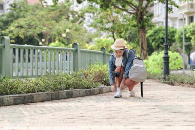 Şehirde fotoğraf makinesi ve sırt çantası olan Asyalı bir kadın var.