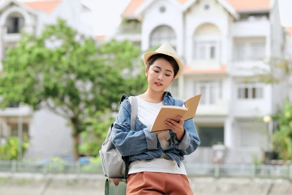 アジアの女性でカジュアル服やベレー帽でバックパック立って路上読書本 — ストック写真