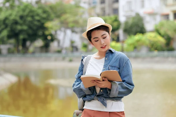 アジアの女性でカジュアル服やベレー帽でバックパック立って路上読書本 — ストック写真