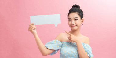 Güzel genç kız öğrenci pembe bir konuşma balonu tutuyor, onu işaret ediyor ve gülümsüyor.