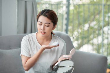 Evdeki kanepede otururken makyajını yapan güzel bir genç kadının fotoğrafı..