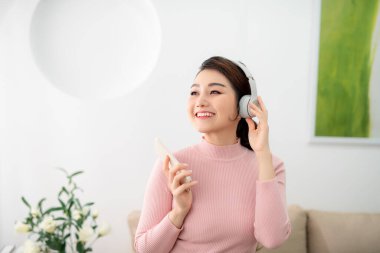 Sevinçle dinleniyor. Evde müzik dinleyen güzel genç bir kadın.